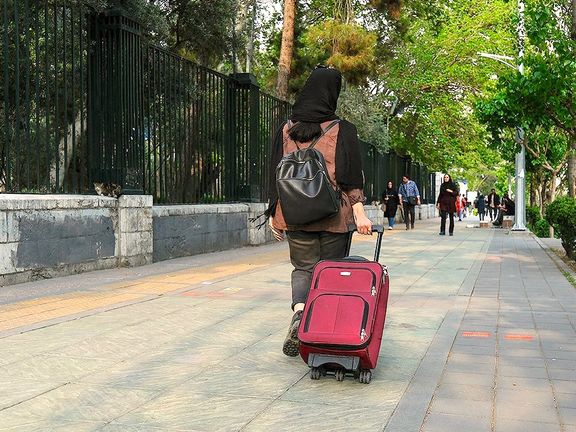 A young woman with a carry on walks outside the University of Tehran, Iran, Undated
