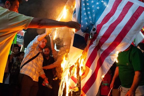 Young men set US flag ablaze in an event celebrating Iran's retaliatory strikes against Israel, June 15, 2025