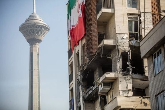 An Iranian flag is hung from a building impacted by an Israeli missile not far away from Tehran's iconic Milad tower, July 25, 2025